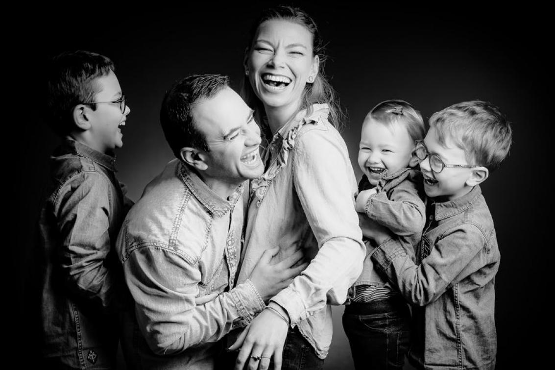 photo de famille en noir et blanc avec la mère, le père et leur trois enfants qui rigolent