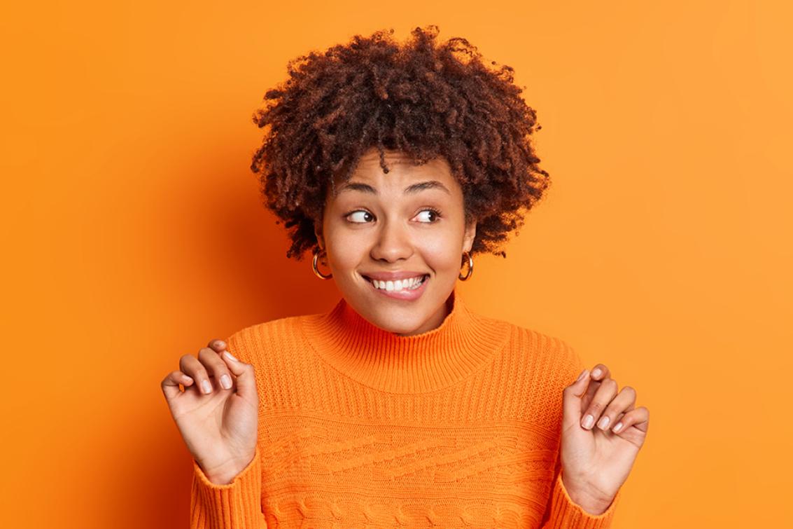 Photographie sur fond orange d'une femme heureuse et impatiente
