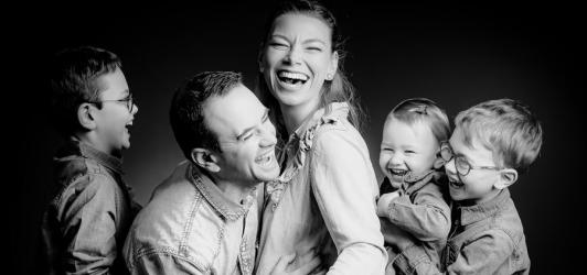 photo de famille en noir et blanc avec la mère, le père et leur trois enfants qui rigolent