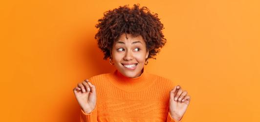 Photographie sur fond orange d'une femme heureuse et impatiente
